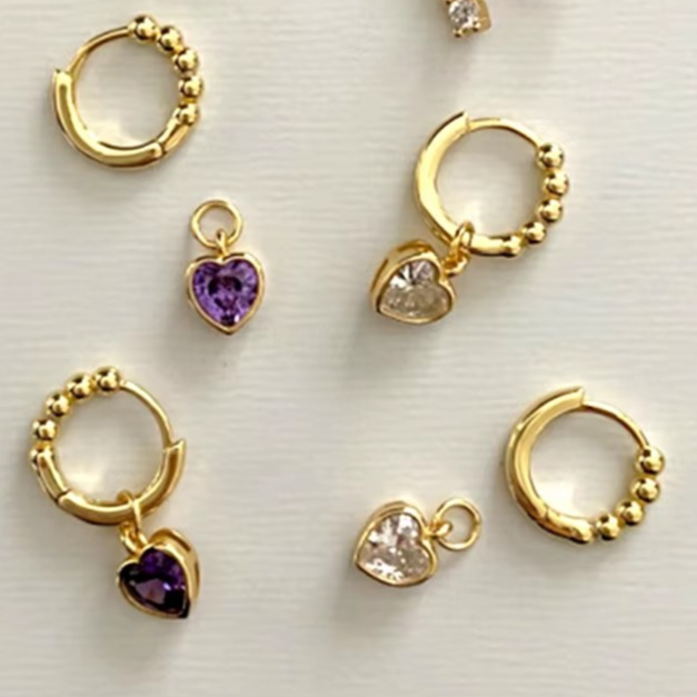 Goldene Huggie-Creolen mit Perlenstruktur und funkelndem Herzanhänger aus Zirkonia. By Bogue