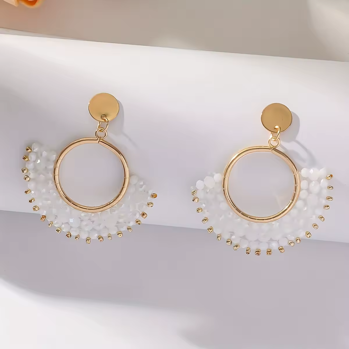 Goldene Boho-Ohrringe mit weißen Perlen, kreisförmiges Design, halbmondförmige Perlenverzierung, eleganter Schmuck auf weißem Hintergrund
