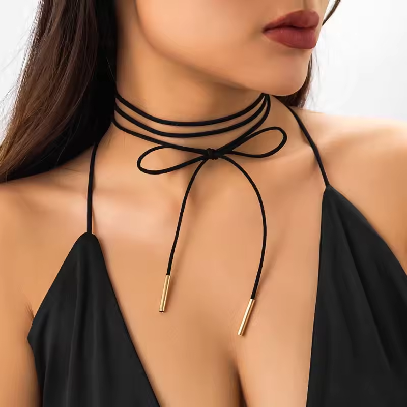 Schwarzes Choker-Halsband aus weichem Wildlederimitat mit goldenen Metallenden, stilvoll geschnürt um den Hals
