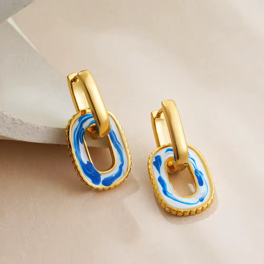 Goldene Hängeohrringe mit rechteckigem weiß-blauen Emaille-Design – einzigartiger Look für elegante Outfits.