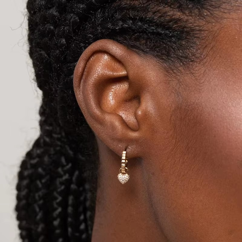 Goldene Huggie-Creolen mit Kugel-Herz-Anhänger. Minimalistisch und perfekt für den Alltag.