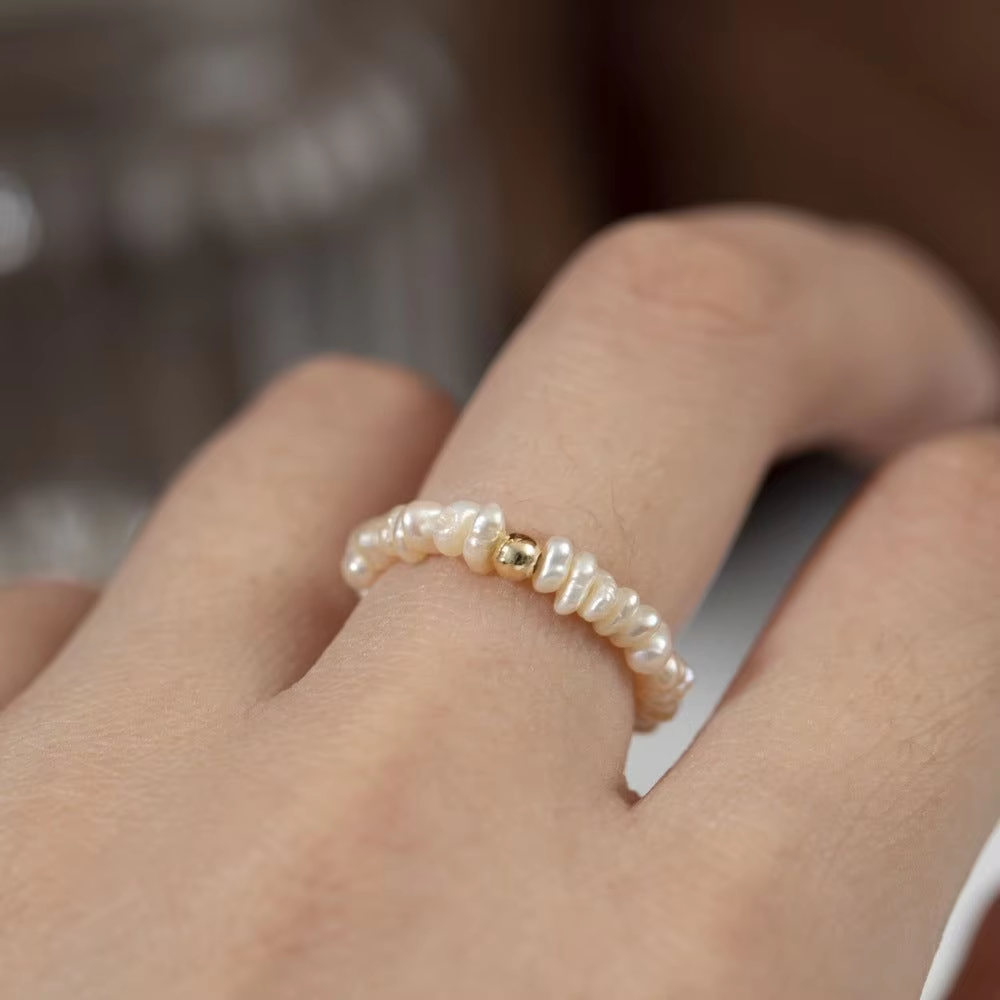 Zarter Süßwasser-Perlenring mit goldener Akzentperle, elastisch und handgefertigt – eleganter Damenring in Weiß und Gold.