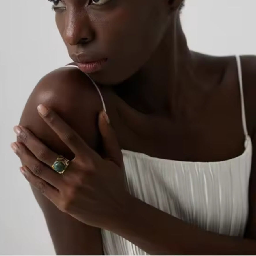 Goldener Statement-Ring aus Edelstahl mit grünem Naturstein, verstellbar, auf weißem Hintergrund.“