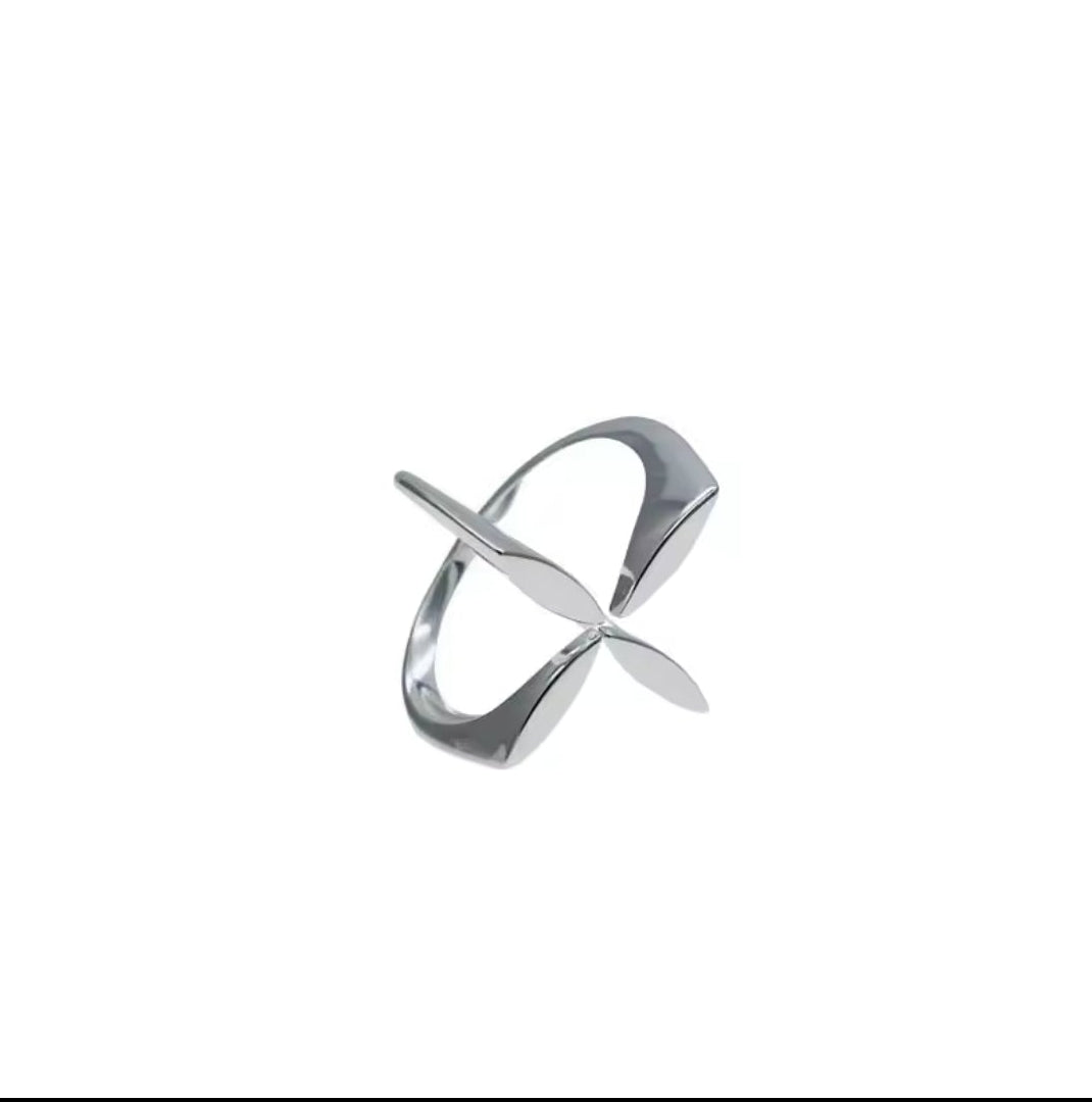 Hand trägt einen silbernen Ring mit floralem Kreuz-Motiv in modernem Design.