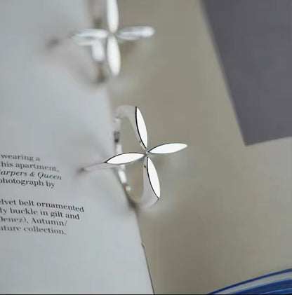 Hand trägt einen silbernen Ring mit floralem Kreuz-Motiv in modernem Design.