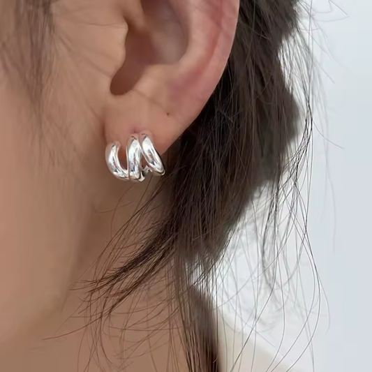 Gedrehte Silber-Creolen mit glänzender Oberfläche – getragen am Ohr, elegantes modernes Design.