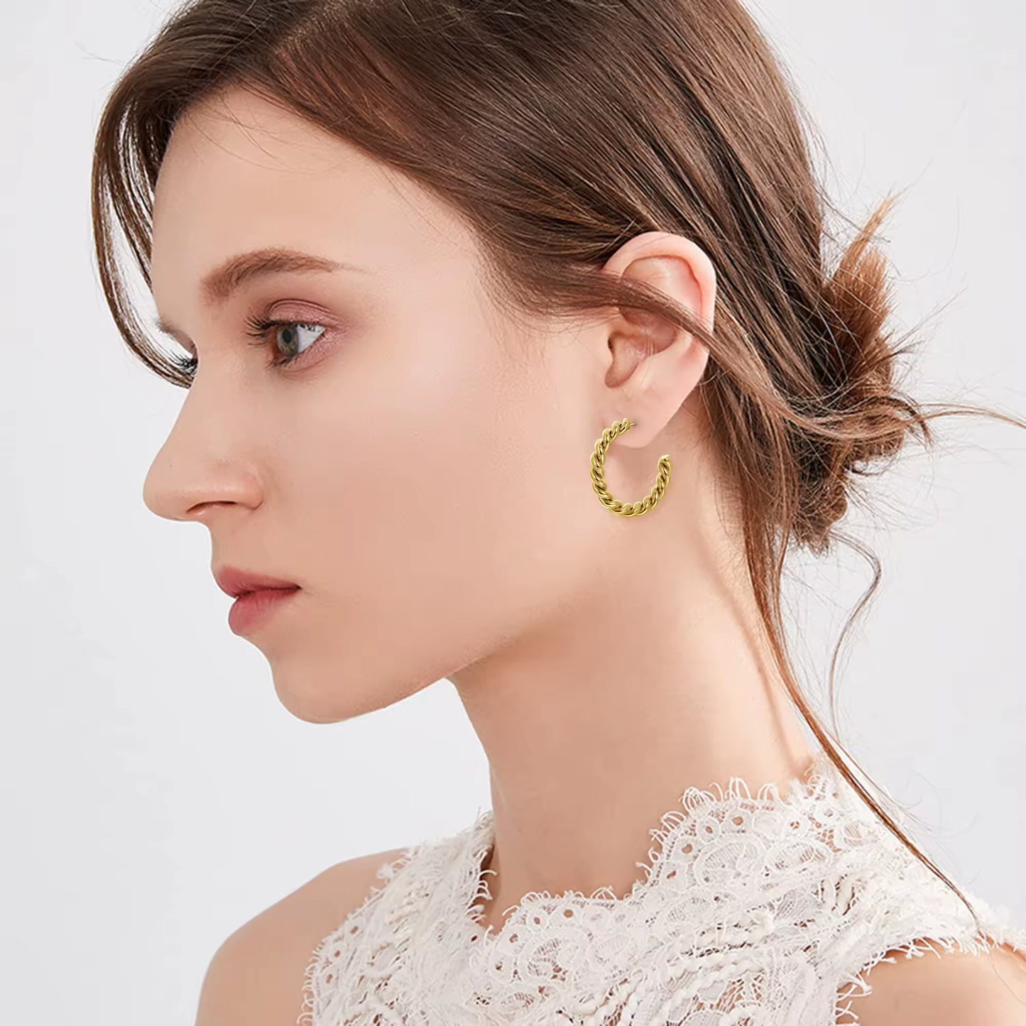 Goldene gedrehte Creolen mit glänzender, polierter Oberfläche auf weißem Hintergrund