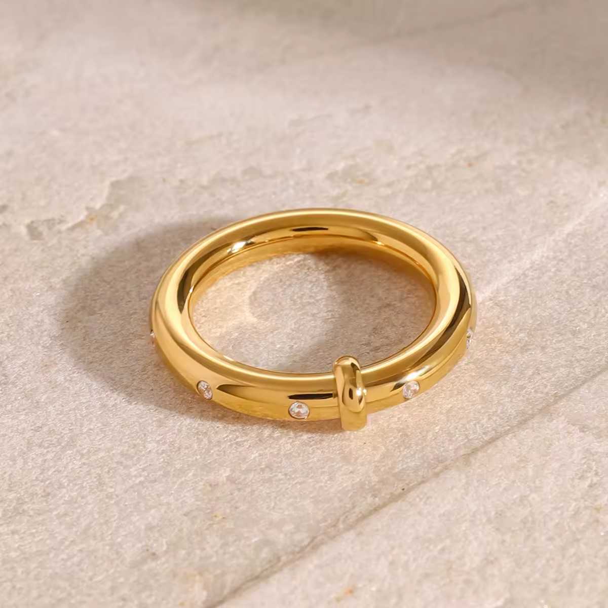 Goldener Ring mit kleinen eingearbeiteten Zirkonia-Steinen, glänzendes Finish, elegantes minimalistisches Design auf weißem Hintergrund